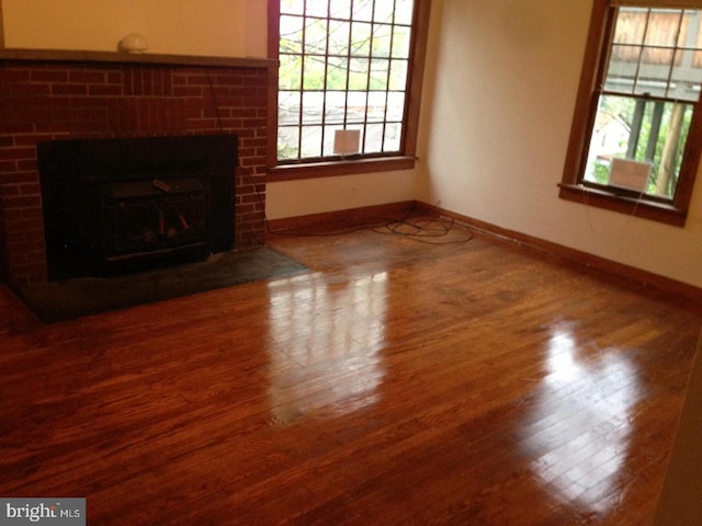 unfurnished living room with hardwood / wood-style flooring and a brick fireplace