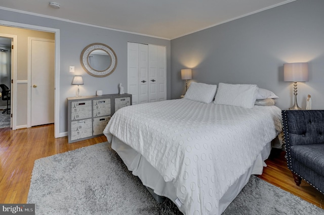 bedroom featuring hardwood / wood-style flooring, ornamental molding, and a closet