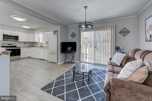 living room with ornamental molding, sink, a chandelier, and light hardwood / wood-style floors