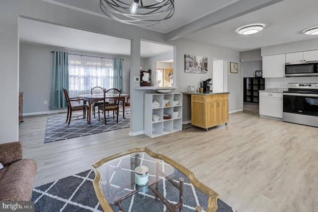 kitchen featuring white cabinetry, appliances with stainless steel finishes, light hardwood / wood-style flooring, and backsplash