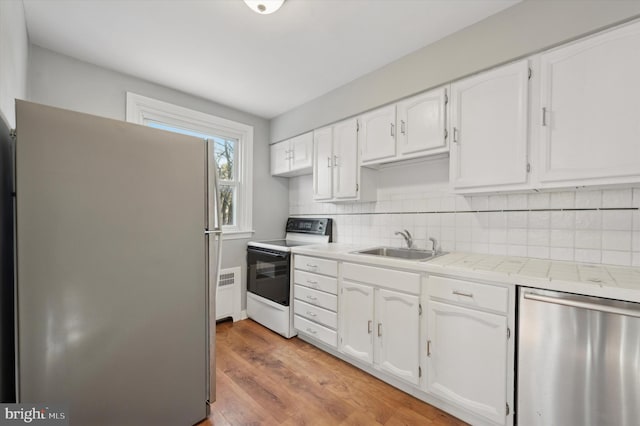 kitchen with appliances with stainless steel finishes, sink, white cabinets, and backsplash