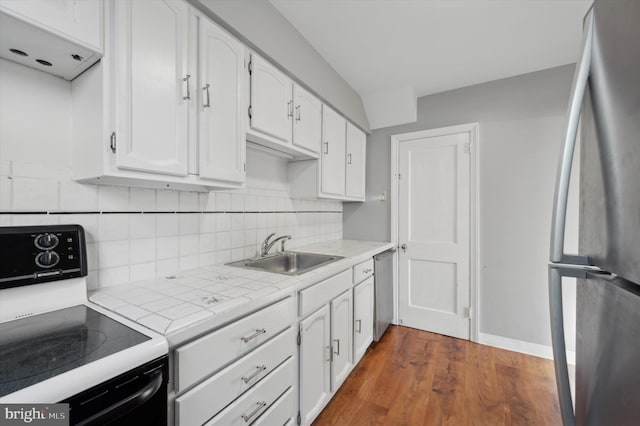 kitchen with sink, appliances with stainless steel finishes, tile counters, white cabinets, and dark hardwood / wood-style flooring