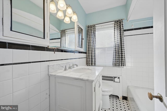 bathroom featuring vanity, a tub to relax in, tile walls, and toilet