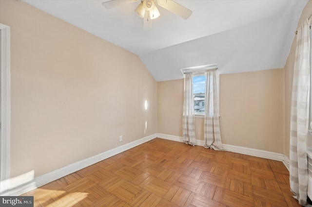 spare room featuring light parquet flooring, vaulted ceiling, and ceiling fan