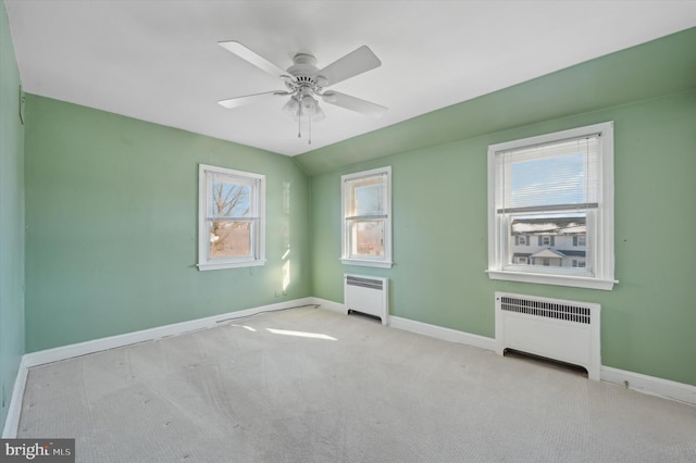 unfurnished bedroom featuring ceiling fan, radiator, vaulted ceiling, and light carpet