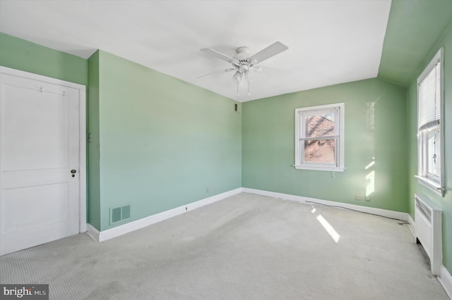 carpeted spare room with lofted ceiling, radiator, and ceiling fan