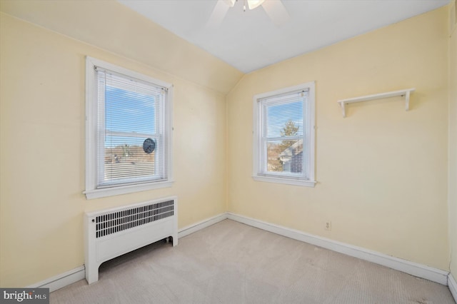 carpeted empty room featuring lofted ceiling, radiator heating unit, and ceiling fan