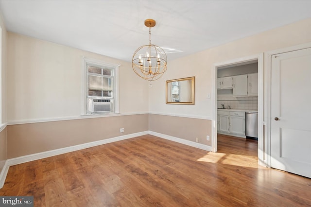 unfurnished dining area featuring cooling unit, sink, a chandelier, and hardwood / wood-style floors