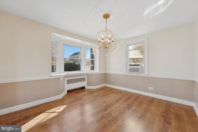 unfurnished dining area with an inviting chandelier, radiator, wood-type flooring, and cooling unit