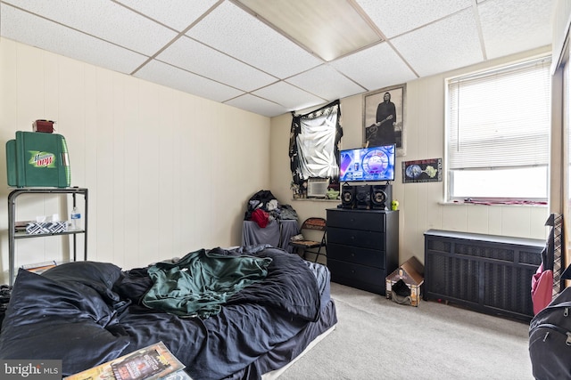 bedroom with a drop ceiling, radiator, and light carpet