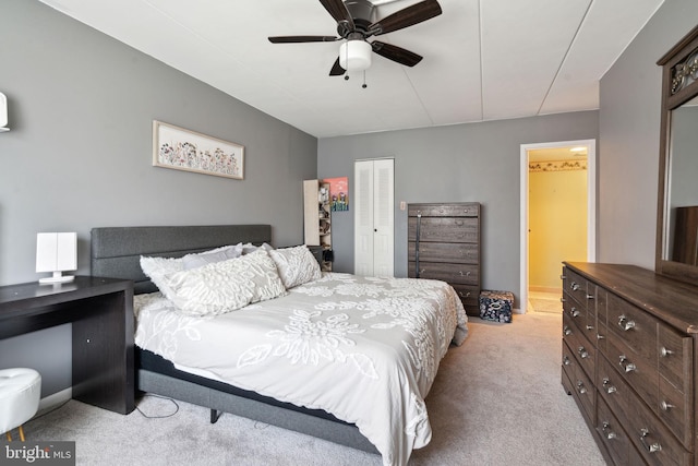 bedroom featuring light colored carpet, ceiling fan, and a closet