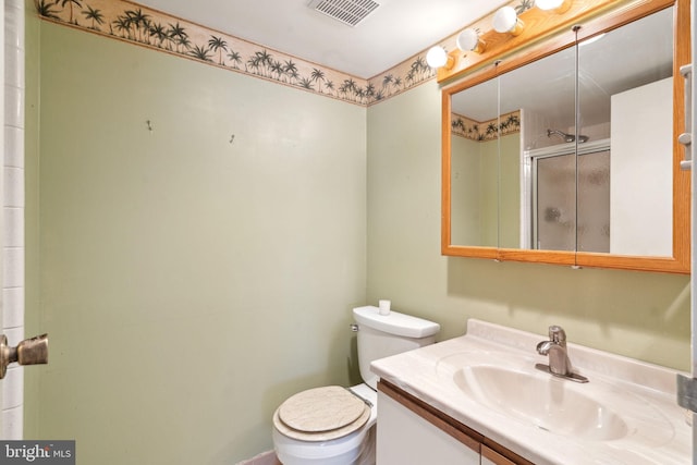 bathroom featuring vanity, toilet, and a shower with shower door