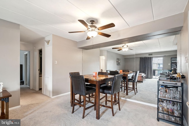 dining space featuring ceiling fan and light colored carpet