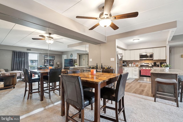 dining space featuring light colored carpet and ceiling fan