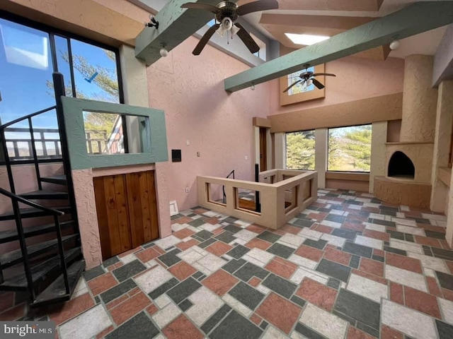 interior space with ceiling fan and lofted ceiling with beams