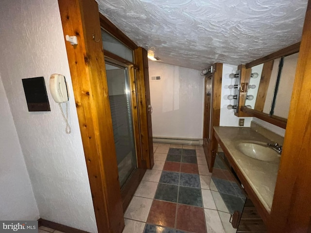 bathroom featuring vanity, a textured ceiling, and baseboard heating