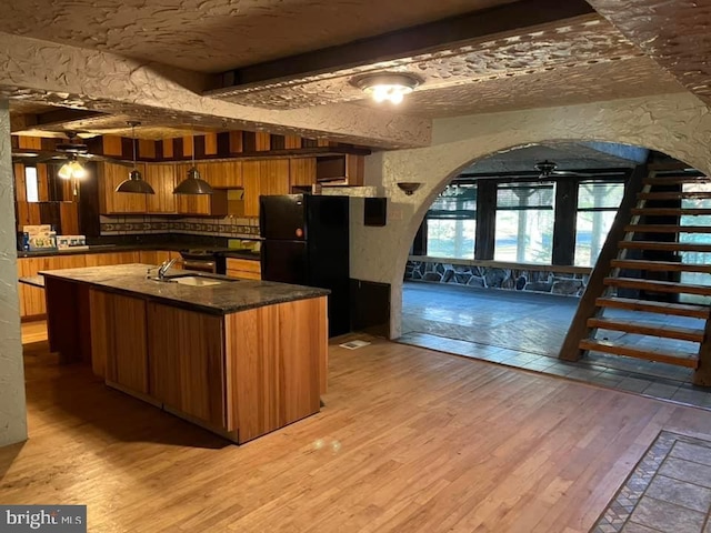 kitchen featuring pendant lighting, sink, ceiling fan, light hardwood / wood-style floors, and black fridge