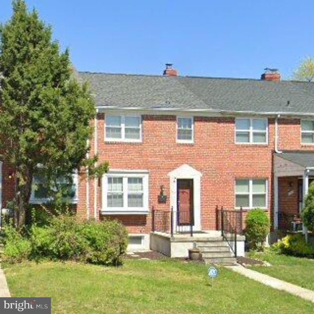 multi unit property with brick siding and a front lawn