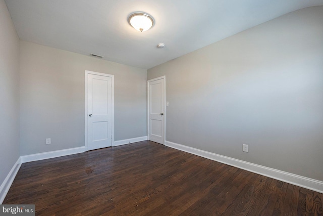 spare room featuring dark wood finished floors, visible vents, and baseboards