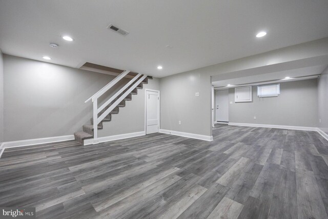below grade area featuring baseboards, stairs, visible vents, and dark wood finished floors