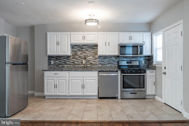 kitchen featuring dark stone counters, stainless steel appliances, and white cabinetry