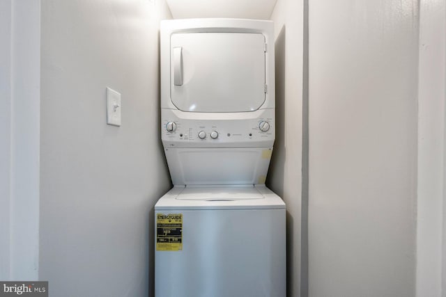 clothes washing area featuring stacked washing maching and dryer and laundry area