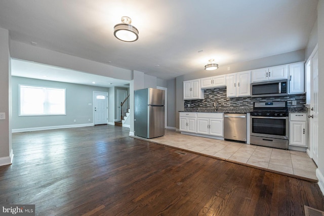 kitchen featuring visible vents, white cabinets, light wood-style flooring, appliances with stainless steel finishes, and backsplash