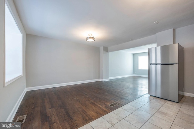 empty room featuring light tile patterned floors, visible vents, and baseboards