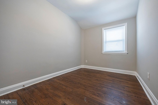 unfurnished room with lofted ceiling, dark wood-style flooring, and baseboards