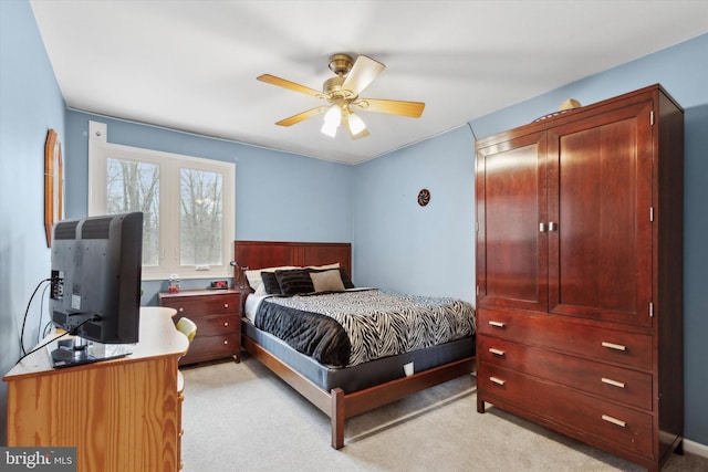 bedroom with light carpet, ceiling fan, and wainscoting