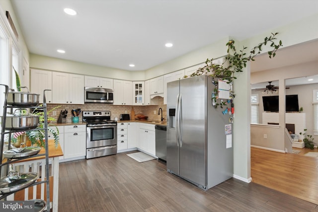 kitchen featuring white cabinetry, glass insert cabinets, stainless steel appliances, and a sink