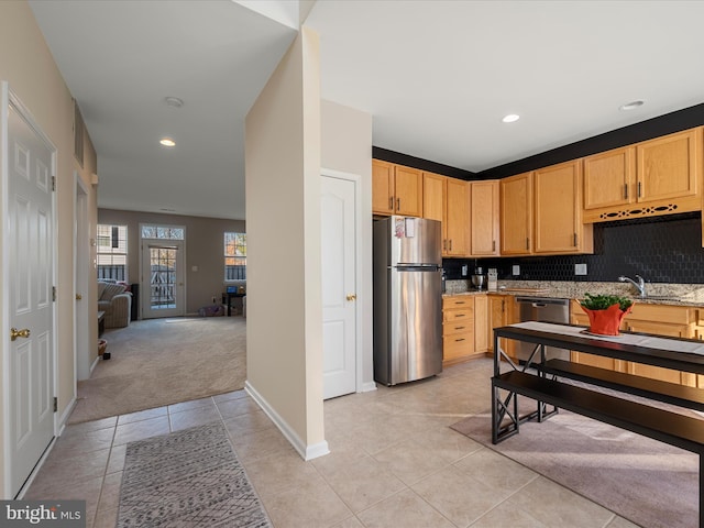 kitchen featuring light tile patterned flooring, sink, light brown cabinets, stainless steel appliances, and light stone countertops