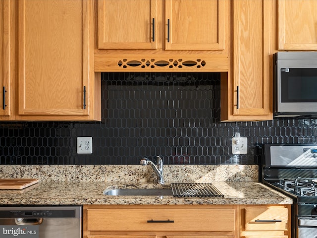 kitchen with light stone counters, sink, decorative backsplash, and stainless steel appliances