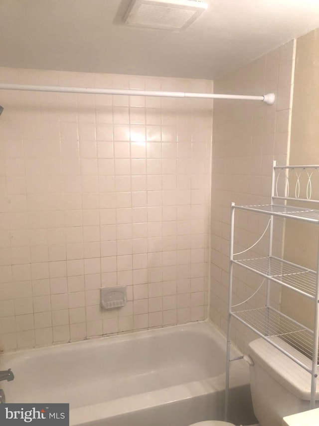 bathroom featuring toilet and tiled shower / bath combo