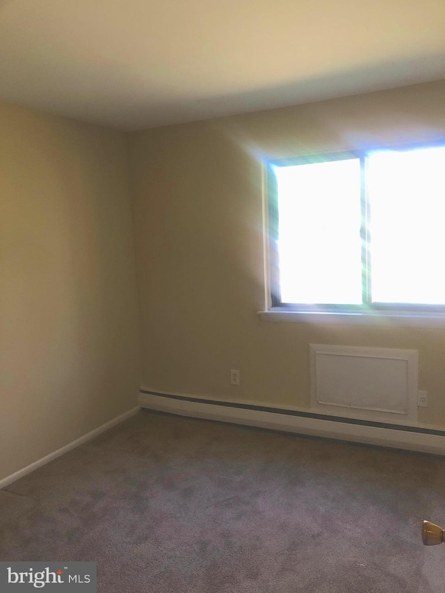 unfurnished room featuring carpet and a baseboard heating unit