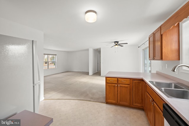 kitchen featuring dishwasher, sink, white fridge, ceiling fan, and kitchen peninsula