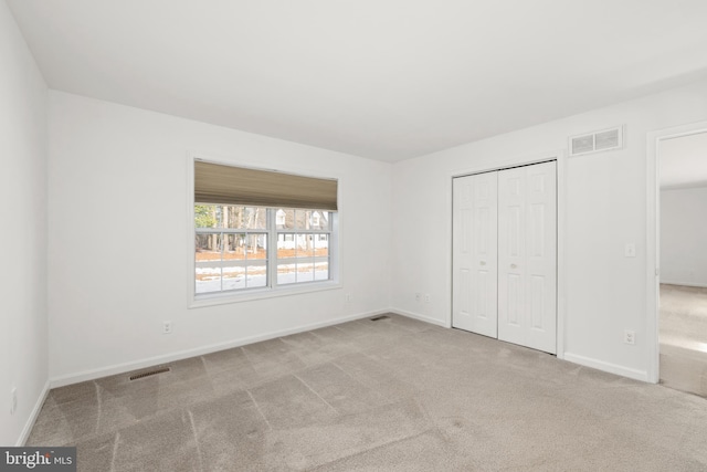 unfurnished bedroom featuring light carpet and a closet