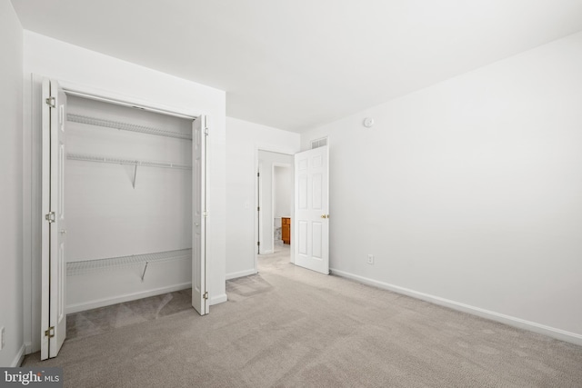 unfurnished bedroom with light colored carpet and a closet