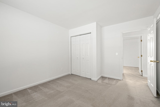 unfurnished bedroom with light carpet and a closet