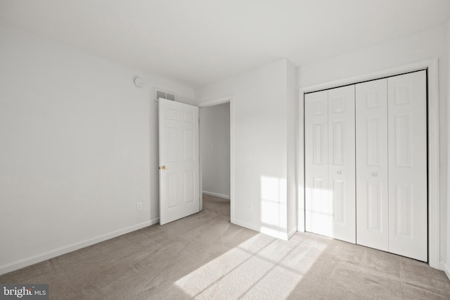 unfurnished bedroom with light colored carpet and a closet