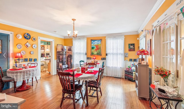 dining area with ornamental molding, a chandelier, and light hardwood / wood-style flooring