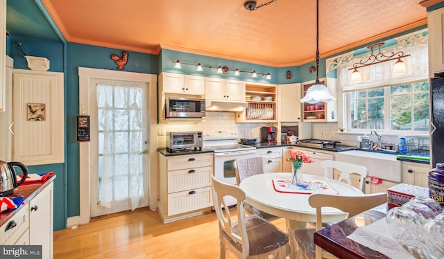 kitchen with white appliances, ornamental molding, decorative backsplash, decorative light fixtures, and light wood-type flooring