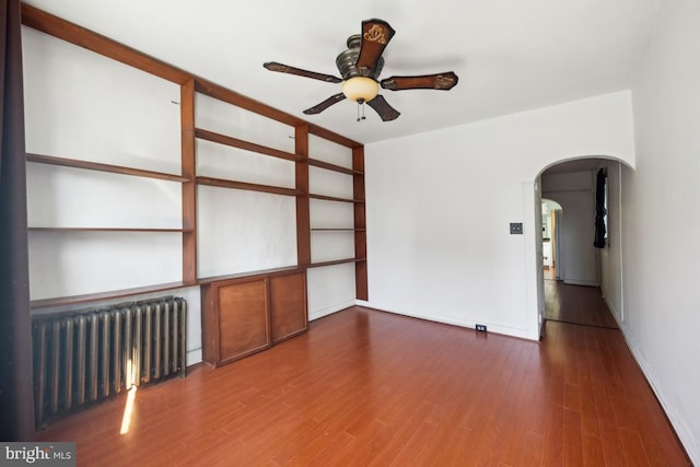 spare room featuring ceiling fan, radiator heating unit, and dark hardwood / wood-style flooring