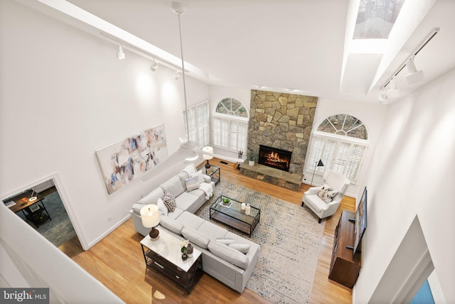 living room with track lighting, wood finished floors, and a stone fireplace