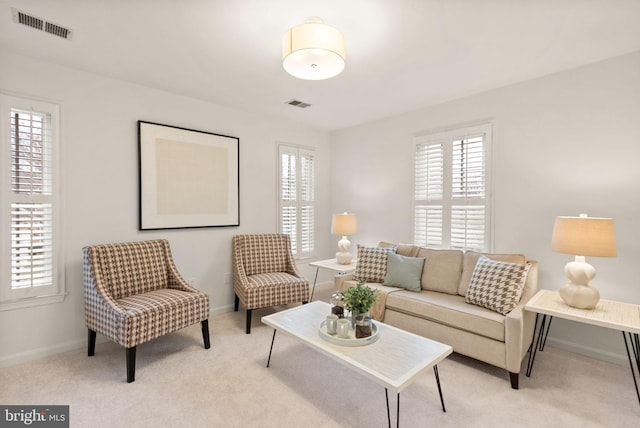 living room featuring plenty of natural light, visible vents, and light colored carpet