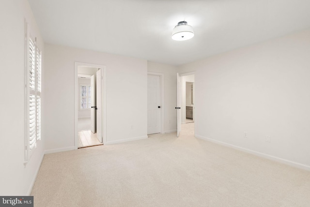 unfurnished bedroom featuring light carpet and baseboards