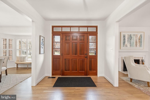 entrance foyer featuring light wood-style floors, a fireplace, plenty of natural light, and baseboards