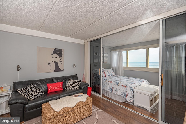 bedroom with hardwood / wood-style flooring, a water view, a textured ceiling, and a closet