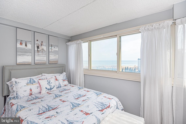 bedroom featuring a water view and a textured ceiling