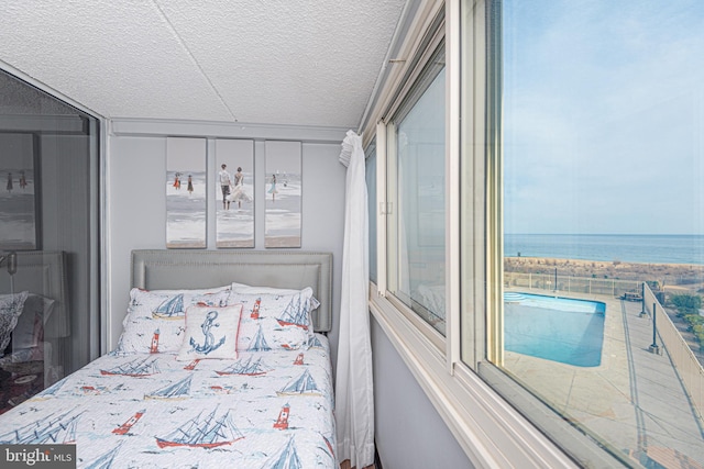 bedroom featuring a water view and a textured ceiling